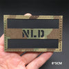 A rectangular tactical patch featuring a camouflage pattern with the letters N.L.D. on a black background.