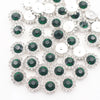 Silver and green crystal rhinestone sew-on buttons arranged in a scattered pattern.