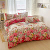 A floral printed duvet cover set featuring pink, red, and yellow flowers with matching pillowcases on a bed.