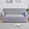 A gray elastic sofa cover protector displayed on a light gray floor.