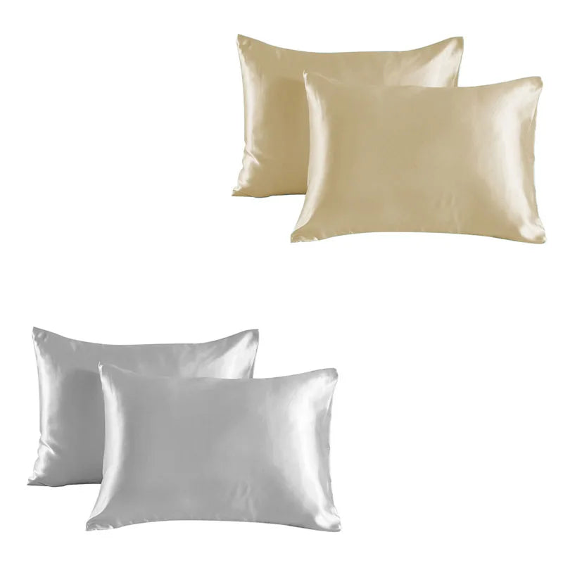 A set of two satin silk pillowcases in a pale gold or champagne color.