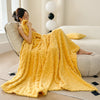 A bright yellow ultra-soft coral fleece blanket draped over a person sitting on a sofa.