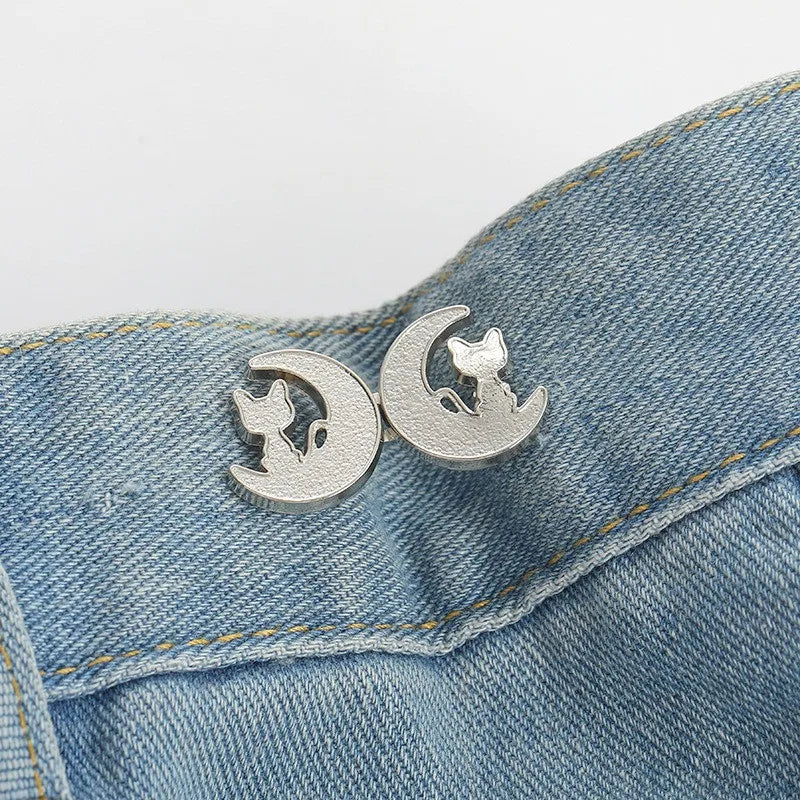 Silver crescent moon button clips featuring a cat silhouette attached to denim fabric