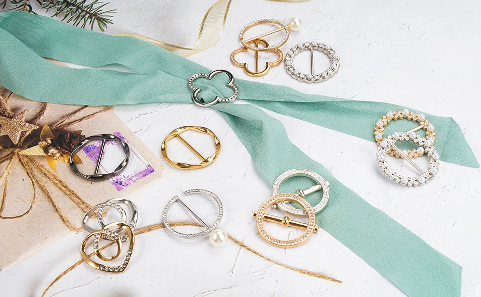 A collection of elegant gold and silver metal ring clips scattered on a light surface with a teal ribbon.