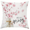 A decorative pillow cover featuring pink cherry blossoms and a glass jar tied with twine.