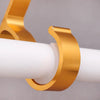 A close-up of a brass curtain rod bracket used for wall mounting, showing its curved shape.