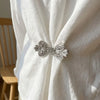 Silver rhinestone clothing clips securing a white fabric scarf or garment