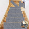 A set of self-adhesive gray textured mats installed on a wooden staircase and door frame.