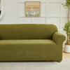Olive green sofa slipcover featuring a jacquard leaves pattern, placed in a bright room.