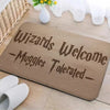 A wooden entrance mat with carved text reading Wizards Welcome Muggles Tolerated