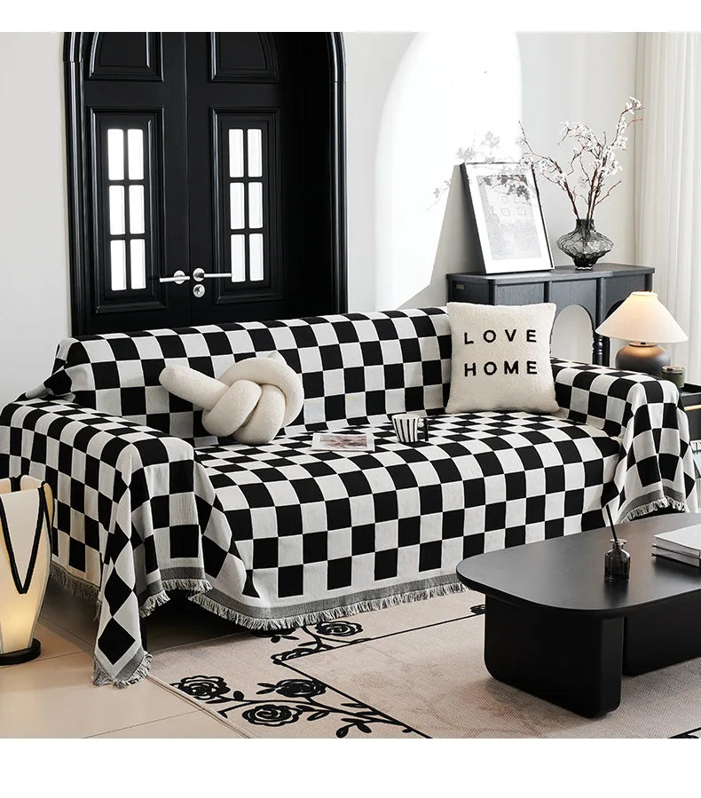 A black and white checkerboard sofa slipcover with a decorative throw and pillows in a modern living room setting.