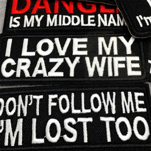 Black embroidered patches with white text featuring phrases like I love my crazy wife and don't follow me I'm lost too