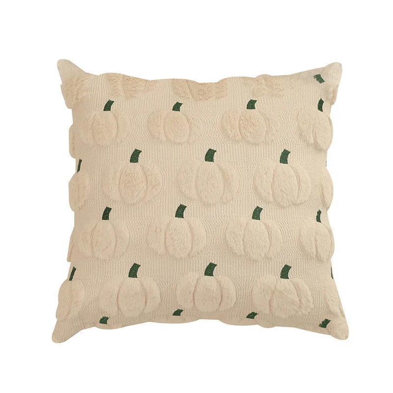 A beige fuzzy throw pillow cover with a repeating pattern of small green pumpkin shapes.