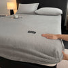 A gray plush jacquard mattress cover is shown on a bed with white pillows and a bedside lamp.