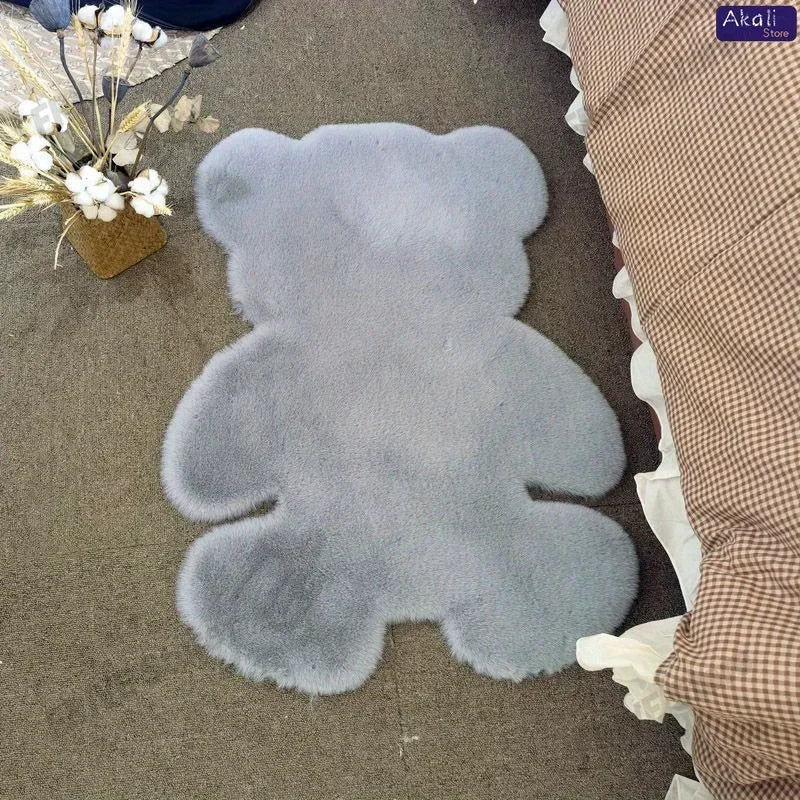 A gray plush bear-shaped non-slip area rug placed on a dark floor.