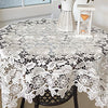 White floral lace tablecloth set on a dark wooden table with a white lantern centerpiece.