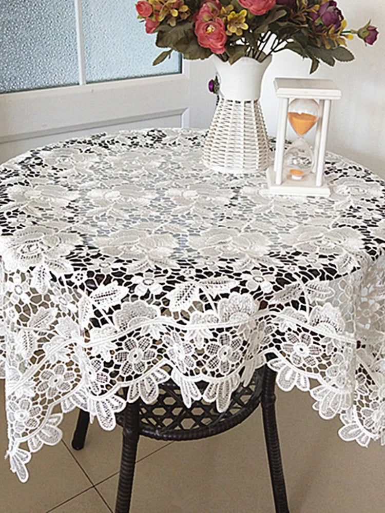 White floral lace tablecloth set on a dark wooden table with a white lantern centerpiece.