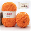 A display of bright orange soft coral velvet yarn in various forms, including a skein and a ball.