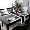 A black dining table set featuring a minimalist black and white placemat and table flag with cutlery and decorative elements.