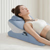 A woman is resting her head on a large blue memory foam body pillow while using a smartphone charger.