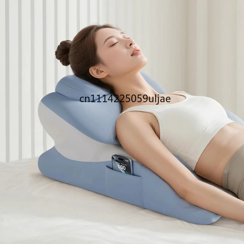 A woman is resting her head on a large blue memory foam body pillow while using a smartphone charger.