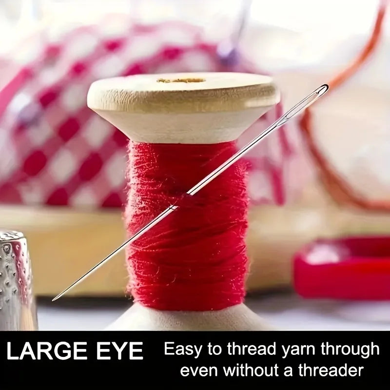 A close-up of a red thread spool with a large eye needle and a stainless steel sewing needle.
