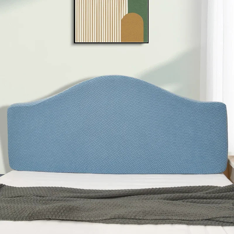 A light blue upholstered headboard cover on a bed with a gray throw blanket.