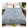 A blue and white embroidered cotton quilted bedspread on a bed with white pillows.