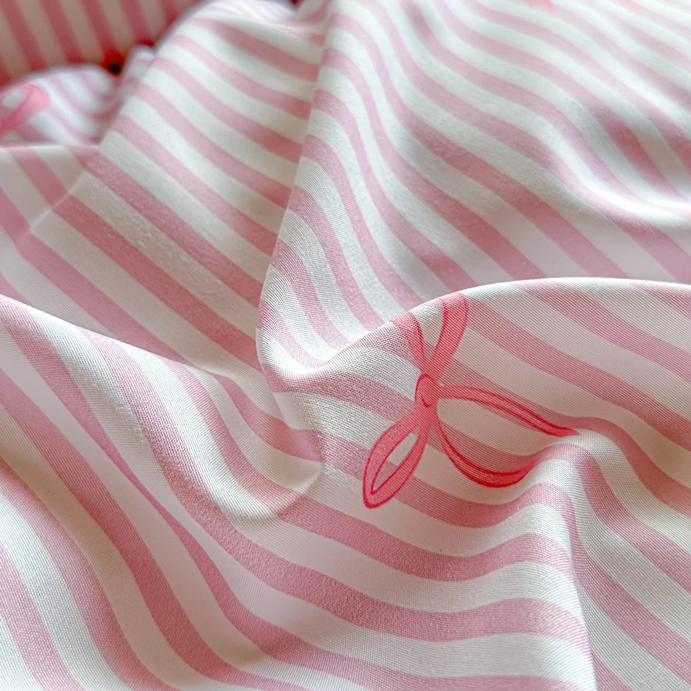 Pink and white striped fabric draped, showing a pink bow print detail on the textile.