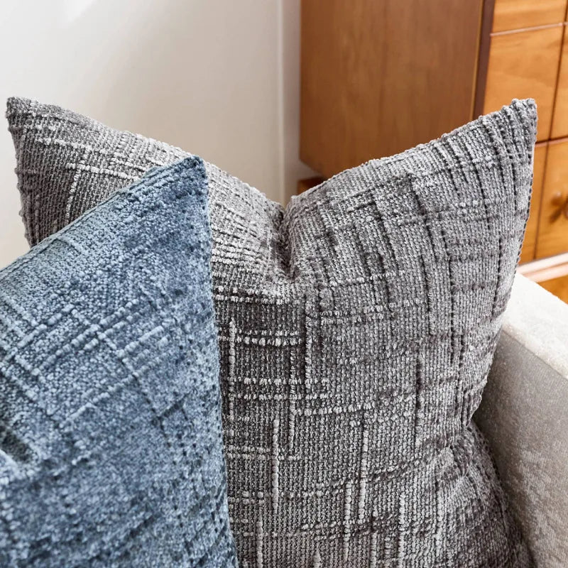 A close-up of a gray boucle texture throw pillow cover resting on a sofa.