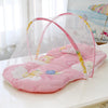 A pink portable baby crib net with soft padding is displayed on a white surface.