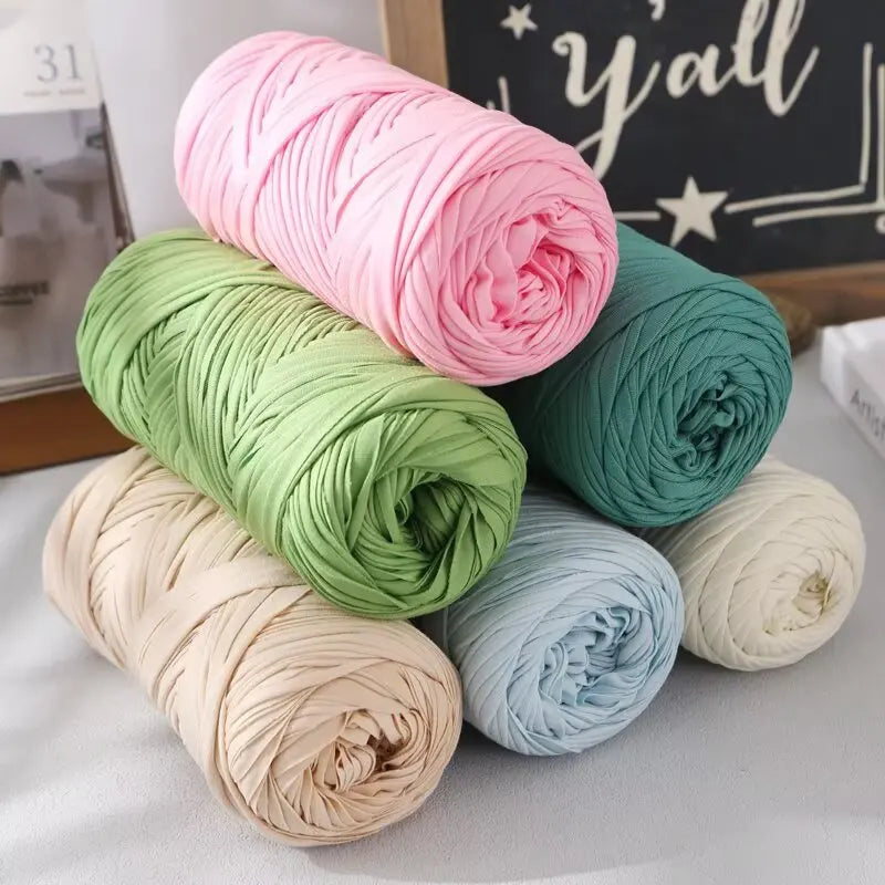 A collection of rolled reusable elastic yarn in various shades including pink, green, beige, and blue.