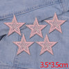 Five pink glitter star patches are displayed on a denim fabric background.