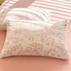 A light pink floral printed pillow cover lying on a pink surface with shadows.