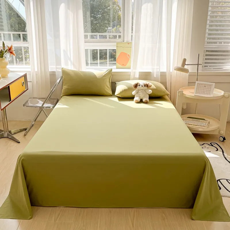 A light green organic cotton bedding set displayed on a bed with white curtains and natural light.