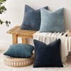 A collection of textured blue and gray chenille pillows displayed on a wooden surface.