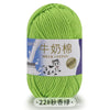 A ball of light green milk cotton yarn with a white label featuring Chinese text and an illustration of a cow.