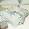 Light green ice silk cooling quilt folded on a white surface with a small metal tag.