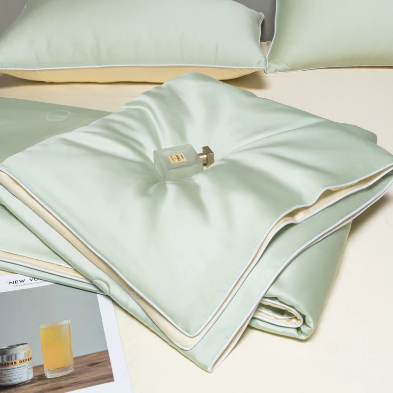 Light green ice silk cooling quilt folded on a white surface with a small metal tag.