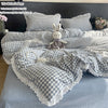 A plaid duvet cover and pillowcase set featuring gray and white checks, with a decorative bunny plush toy.