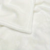 Close-up of a white flannel blanket with a stitched cuff, showing soft texture and folds.