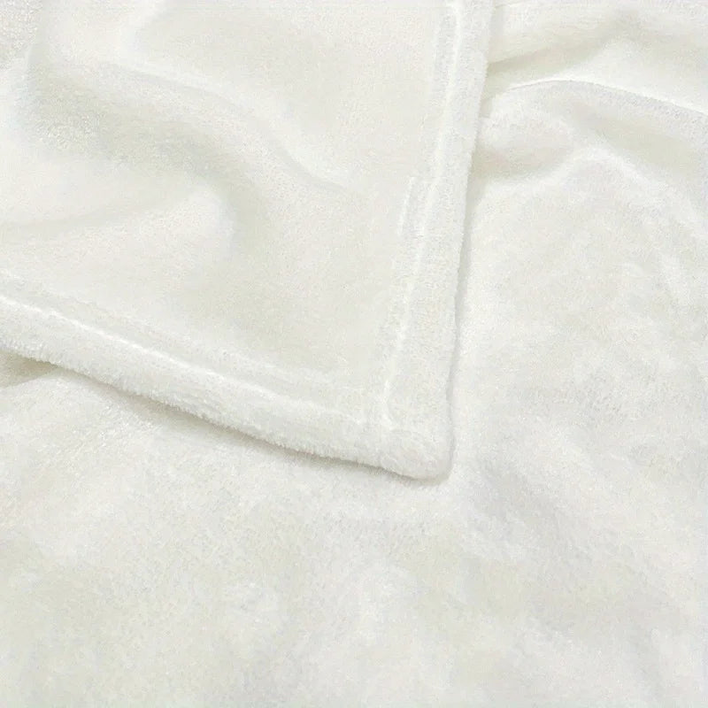 Close-up of a white flannel blanket with a stitched cuff, showing soft texture and folds.