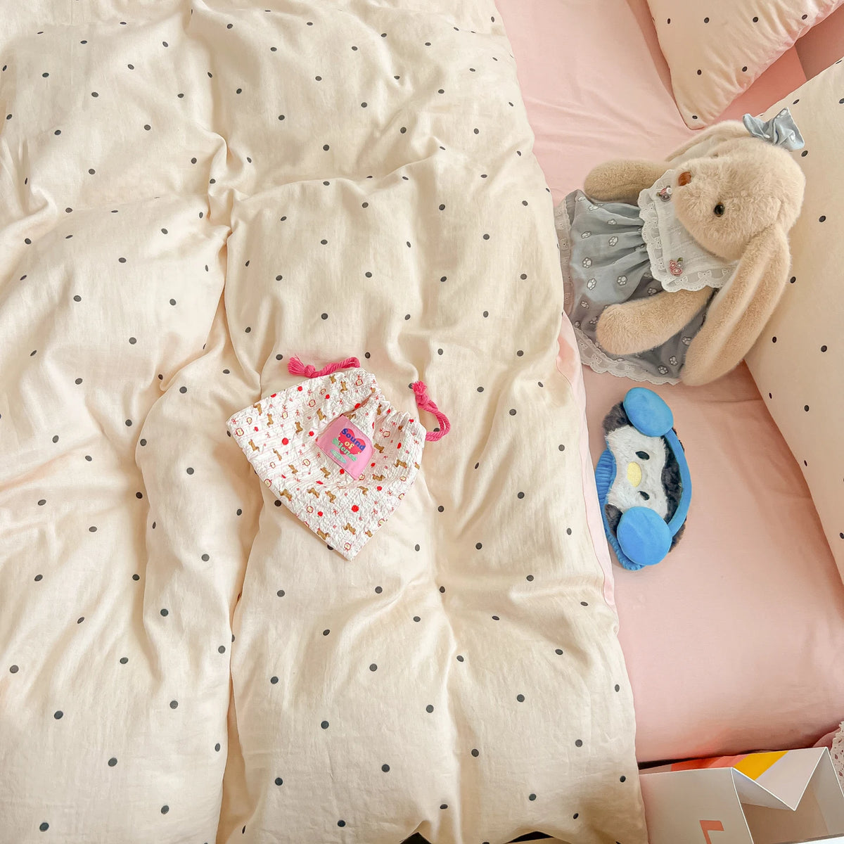 A pink polka dot duvet cover set with a light pink pillow and a small stuffed animal