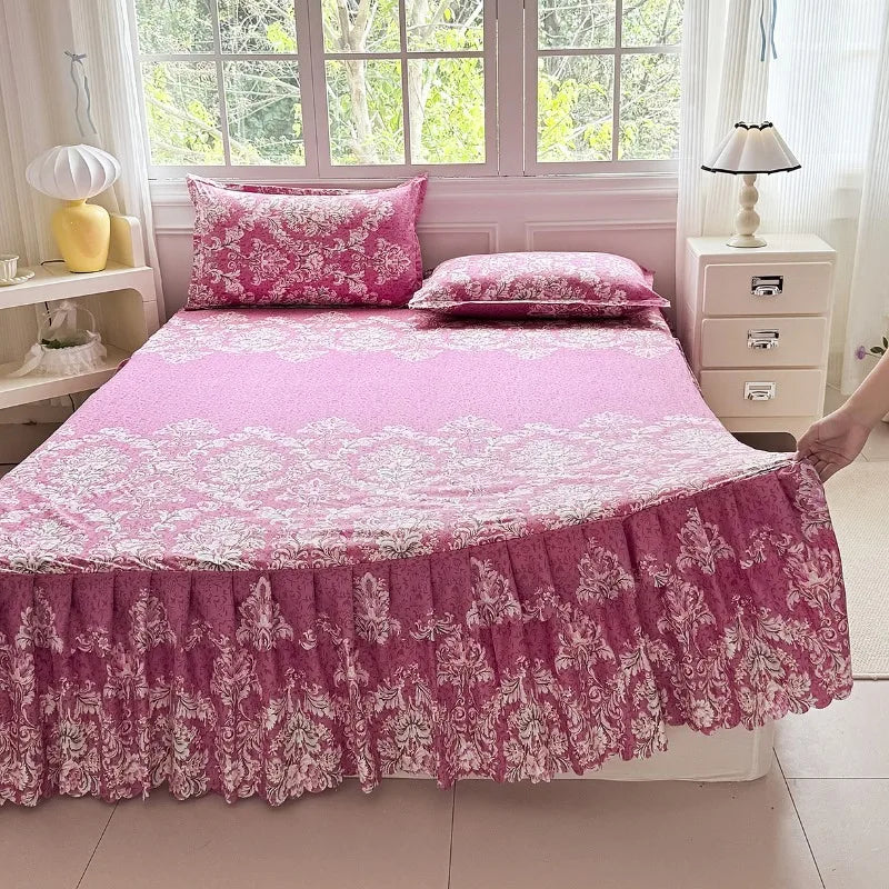 A pink floral print bed skirt set featuring a pink comforter and pillow on a bed.
