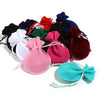 A collection of ten velvet drawstring gift bags in various colors including red, purple, green, black, and pink.