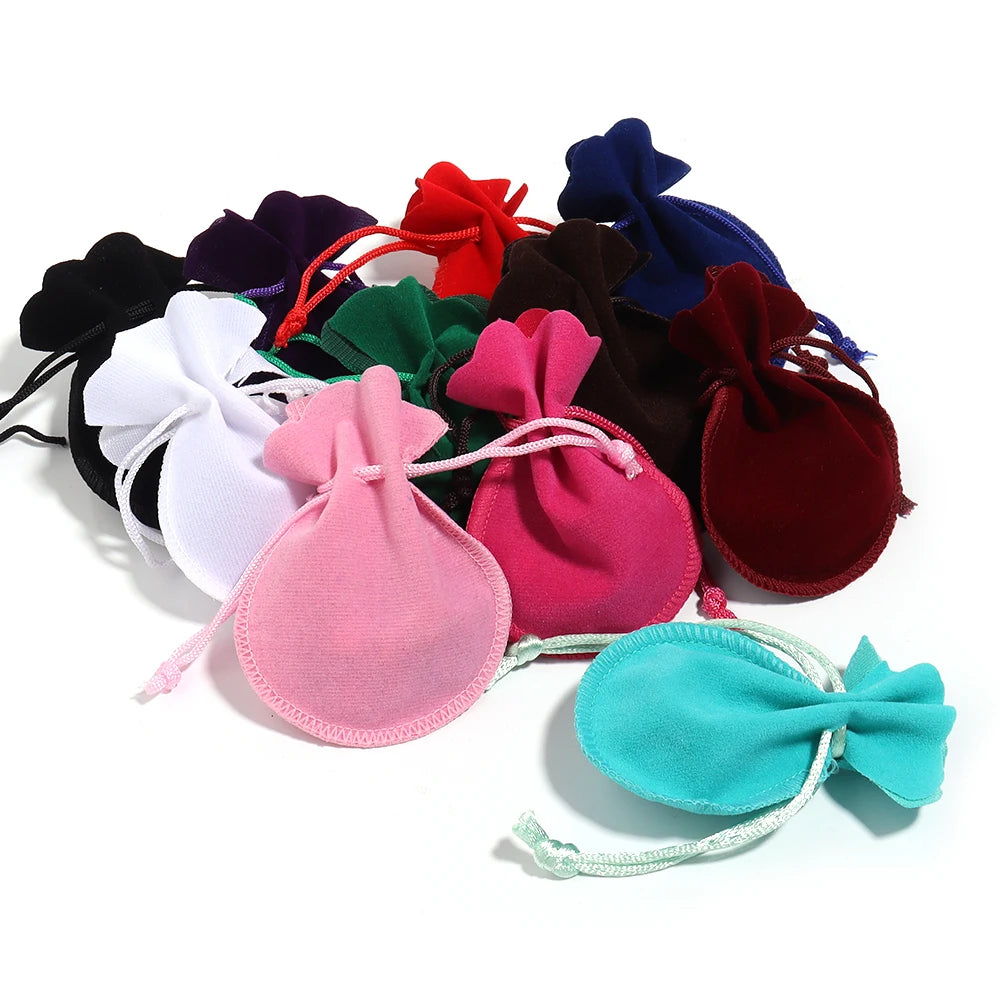 A collection of ten velvet drawstring gift bags in various colors including red, purple, green, black, and pink.