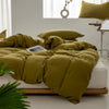 A mustard green minimalist duvet cover is displayed on a bed with white linens and natural wood framing.