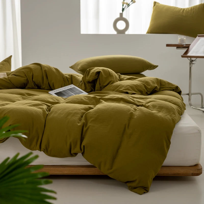 A mustard green minimalist duvet cover is displayed on a bed with white linens and natural wood framing.