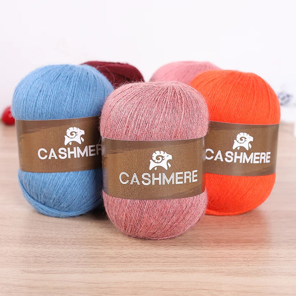 Three skeins of yarn in blue, pink, and orange colors with brown labels for knitting projects