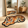 An orange and black tiger plush cartoon area rug lying on a light wood floor in front of a large mirror.